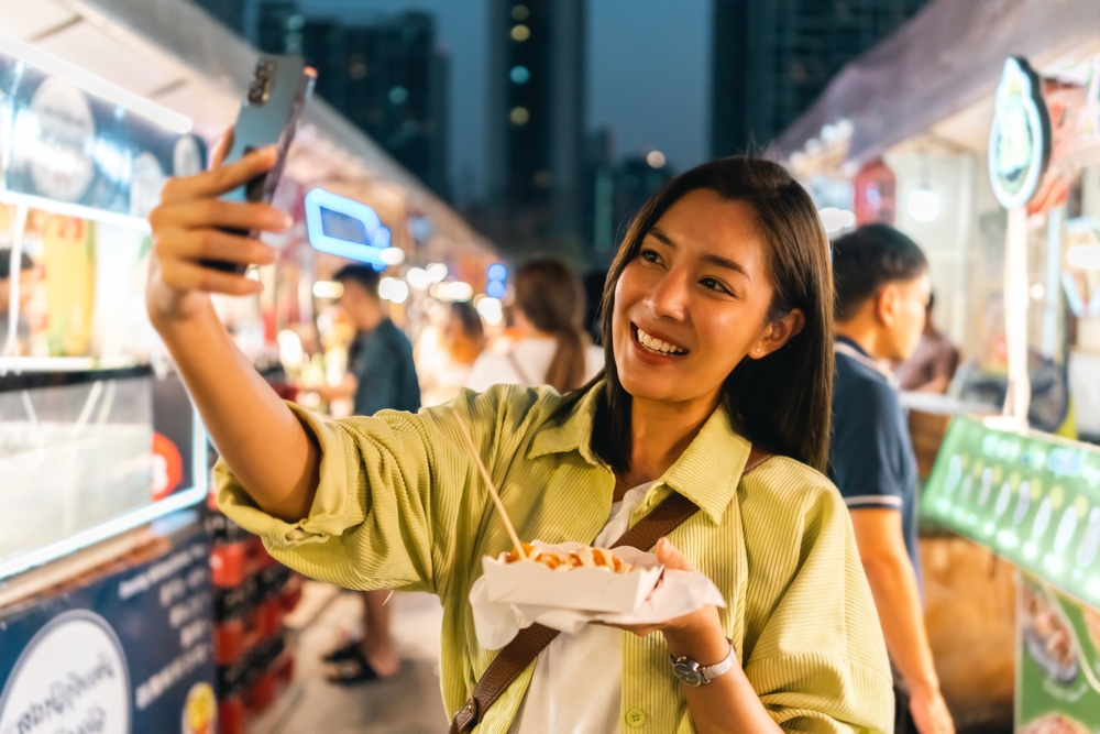 A woman enjoying food at one of Ratchada’s night markets, a big part of living in Ratchada Bangkok.