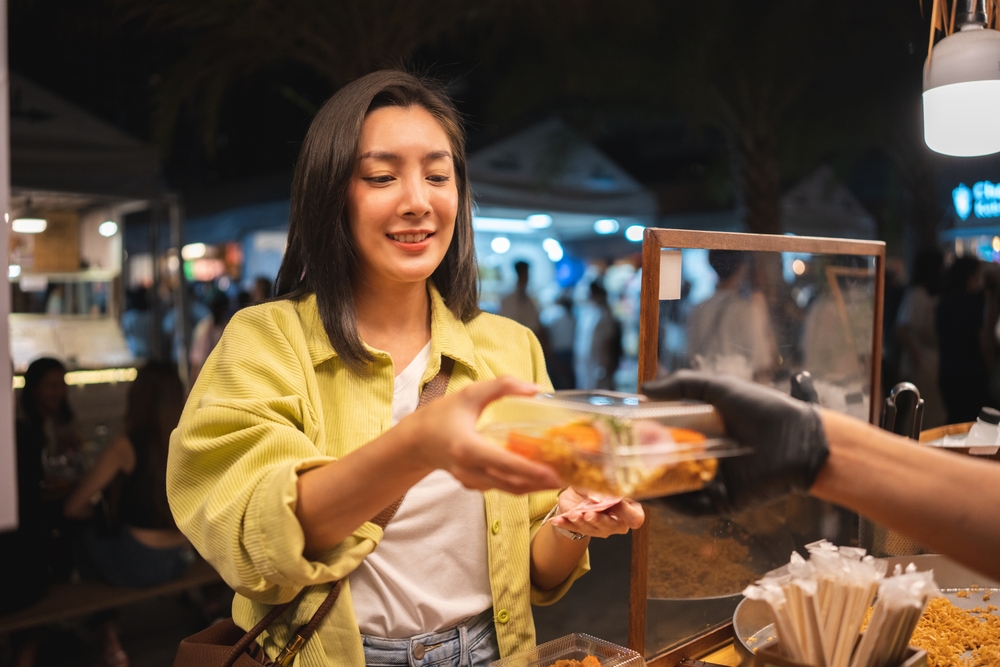 A young woman buying street food at the Jodd Fairs night market.