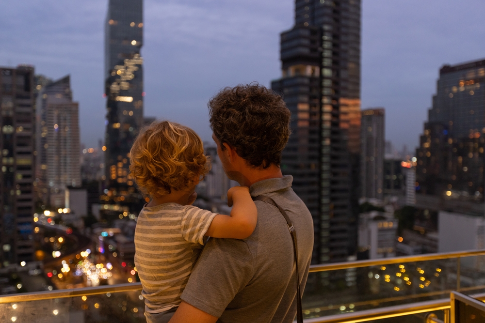 A parent and a child looking out at Bangkok’s cityscape. There are many toddler-friendly activities.