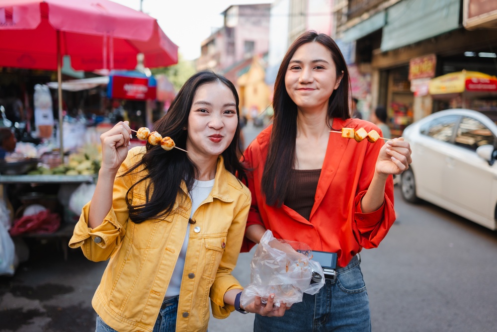 Two friends enjoying street food in Bangkok