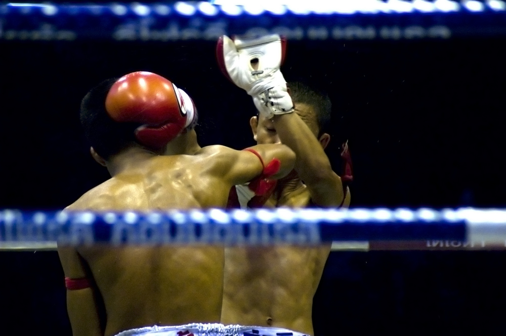 A Muay Thai fight taking place in Lumpini Stadium, one of the major boxing stadiums in Bangkok.